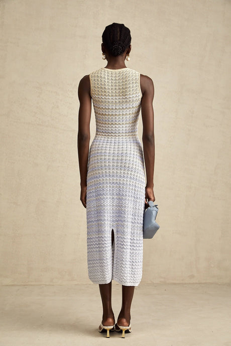A woman wearing a long fitted ribbed knit dress with contrasting color panels and a midi length skirt