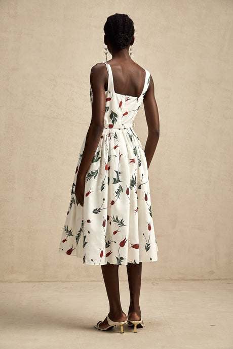A woman wearing a long floral print dress with a poplin fabric standing in a natural outdoor setting