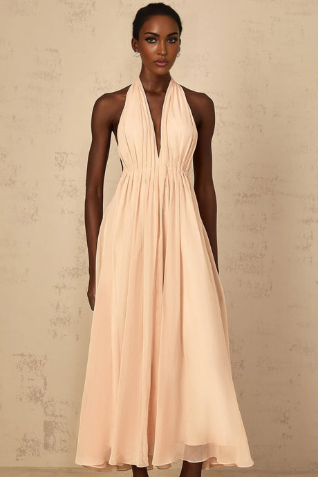 A woman wearing a long flowing halterneck maxi dress with shirred bodice and tulle skirt