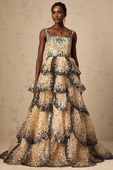 A woman wearing a long flowing maxi dress with tiered layers and shimmering sequin details resembling flower petals