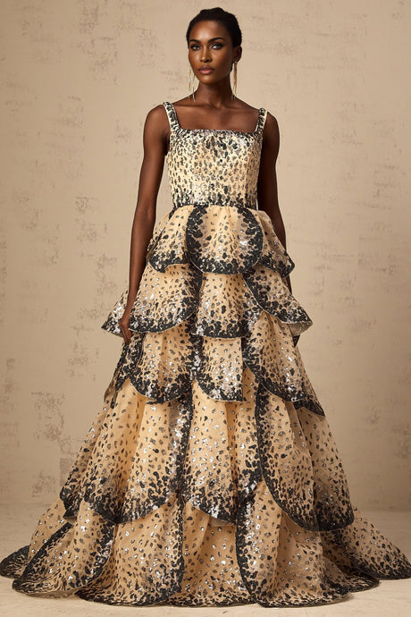 A woman wearing a long flowing maxi dress with tiered layers and shimmering sequin details resembling flower petals