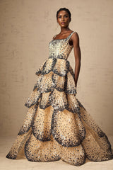 A woman wearing a long flowing maxi dress with tiered layers covered in shimmering sequins resembling delicate flower petals