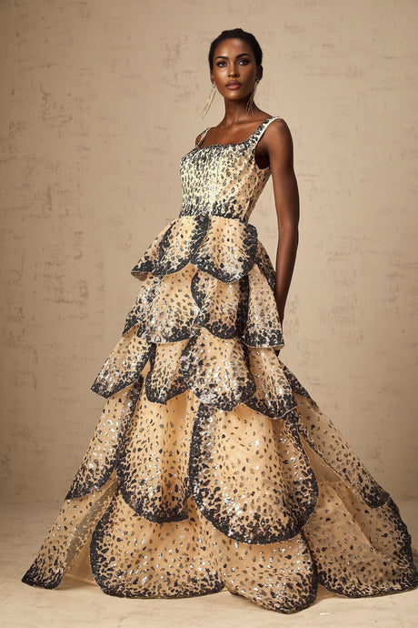 A woman wearing a long flowing maxi dress with tiered layers covered in shimmering sequins resembling delicate flower petals