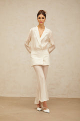 A woman wearing a long flowing white maxi dress with sheer panels standing in a relaxed pose