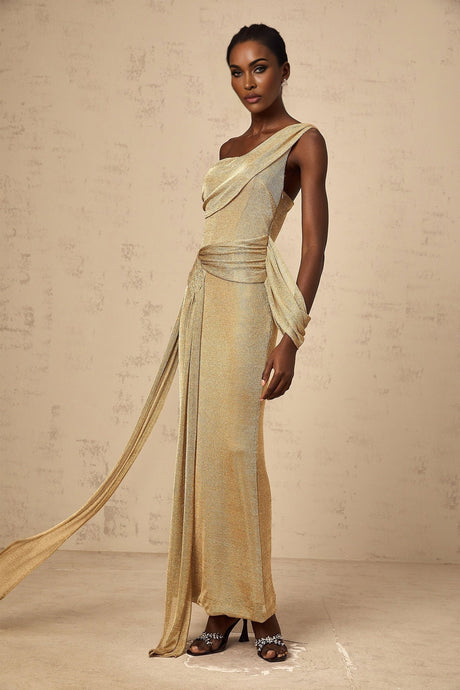 A woman wearing a long gold maxi dress with a ribbon design and gathered fabric details