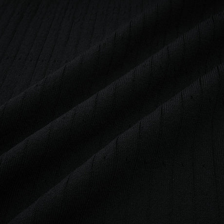 A woman wearing a long knit midi dress with lace trim details at the neckline and hem standing in a neutral background