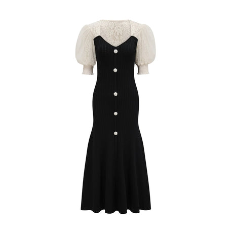 A woman wearing a long knit midi dress with lace trim details at the neckline and hem standing in a neutral pose against a plain background