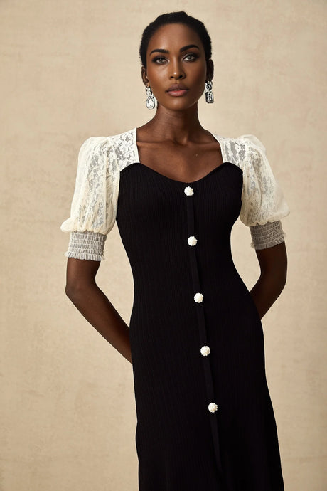 A woman wearing a long knit midi dress with lace trim details standing in a neutral pose
