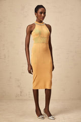 A woman wearing a long knitted dress with faux pearl embellishments throughout the design