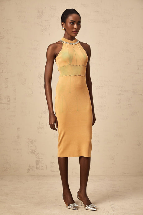 A woman wearing a long knitted dress with faux pearl embellishments throughout the design