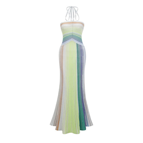 A woman wearing a long metallic knit maxi dress with a backless design standing in a relaxed pose