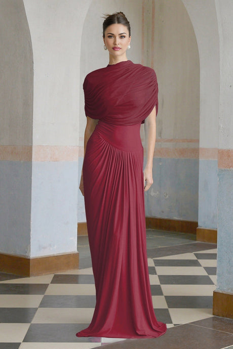 A woman wearing a long red asymmetric maxi dress with pleated details and a flowing skirt