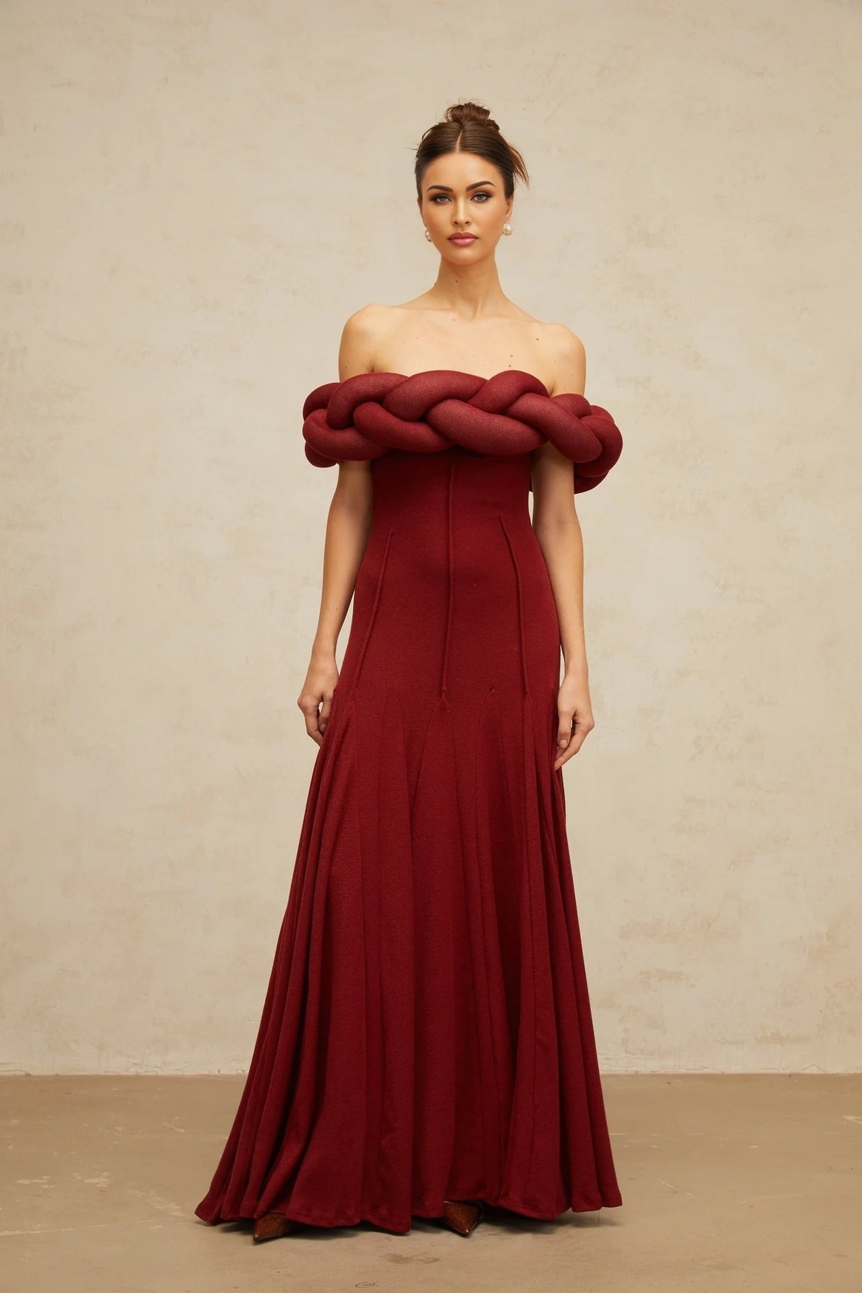 A woman wearing a long red knitted maxi dress with a braided design pattern