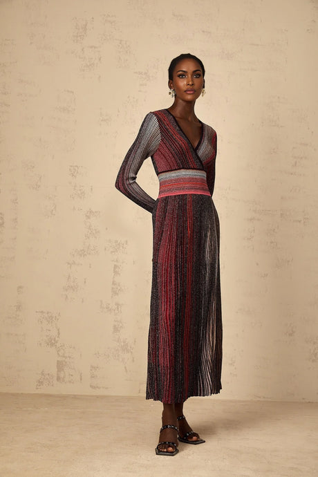 A woman wearing a long red maxi dress with long sleeves featuring sequin striped details and a knit fabric