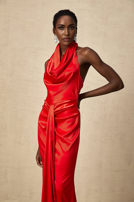 A woman wearing a long red satin dress with a halter neckline and draped design