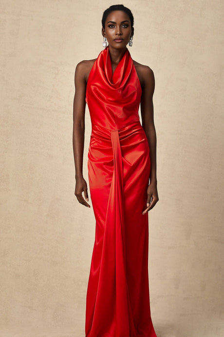 A woman wearing a long red satin dress with a halter neckline and draped fabric flowing to the floor