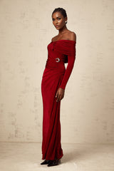 A woman wearing a long red velvet dress with ruched detailing and a fitted silhouette