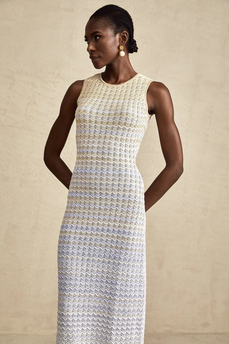 A woman wearing a long ribbed knit dress with contrasting colors featuring a fitted silhouette and midi length