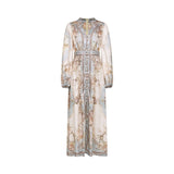 A woman wearing a long sleeve floral print boho dress with a flowing skirt and feminine silhouette in a nature inspired setting