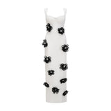 A woman wearing a long white bandage dress with floral applique detailing standing against a plain background