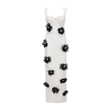 A woman wearing a long white bandage dress with floral applique detailing standing against a plain background