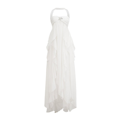 A woman wearing a long white chiffon maxi dress with ruffles and a halter neckline