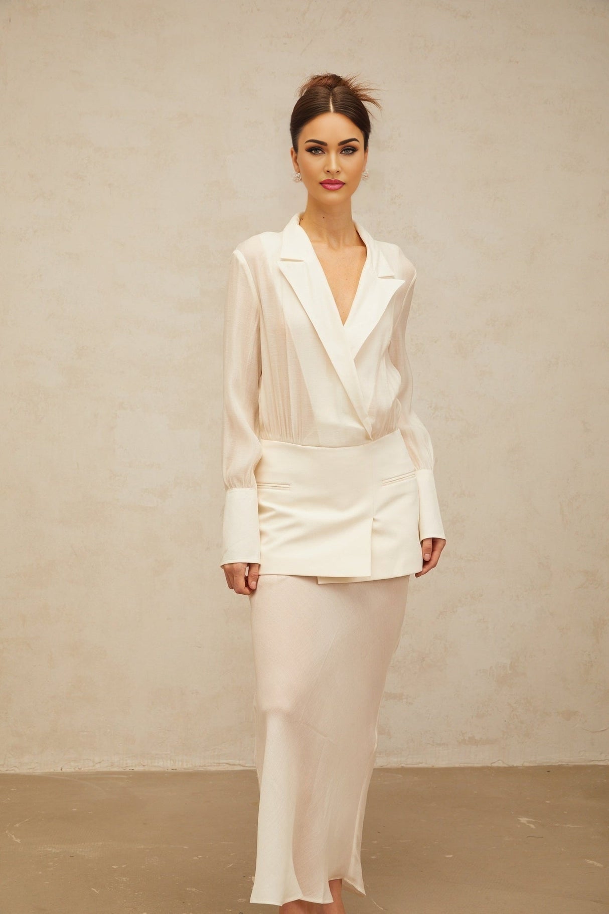 A woman wearing a long white flowy maxi dress with sheer panels standing in a relaxed pose