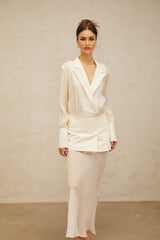 A woman wearing a long white flowy maxi dress with sheer panels standing in a relaxed pose