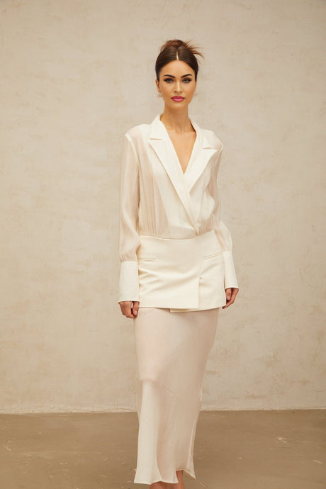 A woman wearing a long white flowy maxi dress with sheer panels standing in a relaxed pose
