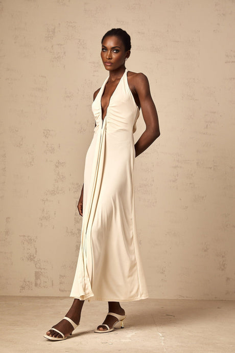 A woman wearing a long white maxi dress with a deep V neckline and draped fabric detail