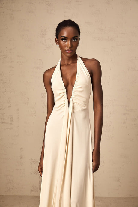 A woman wearing a long white maxi dress with a deep V neckline and draped fabric detail