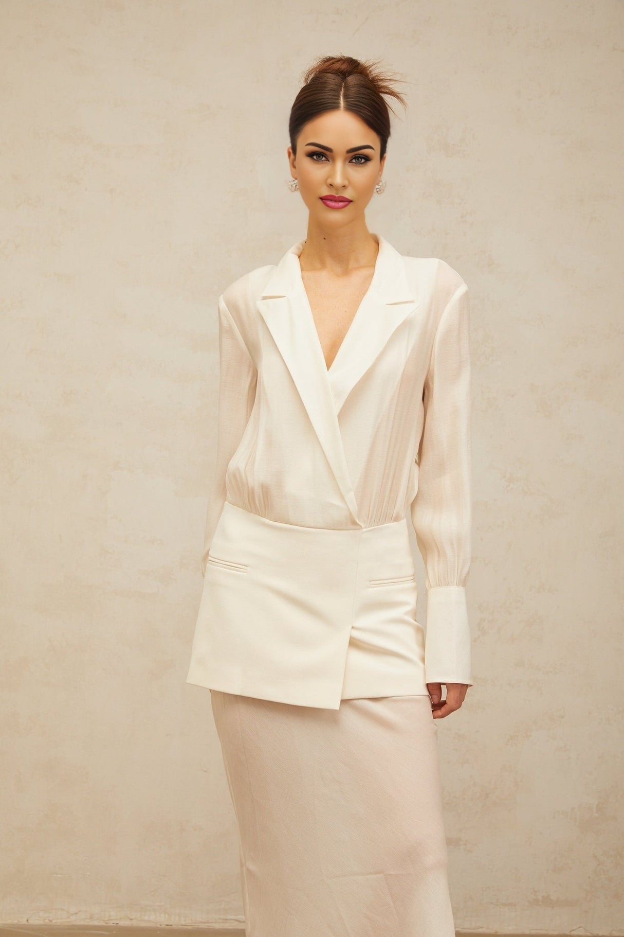 A woman wearing a long white maxi dress with sheer paneling standing in a relaxed pose