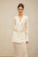 A woman wearing a long white maxi dress with sheer paneling standing in a relaxed pose