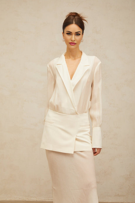 A woman wearing a long white maxi dress with sheer paneling standing in a relaxed pose
