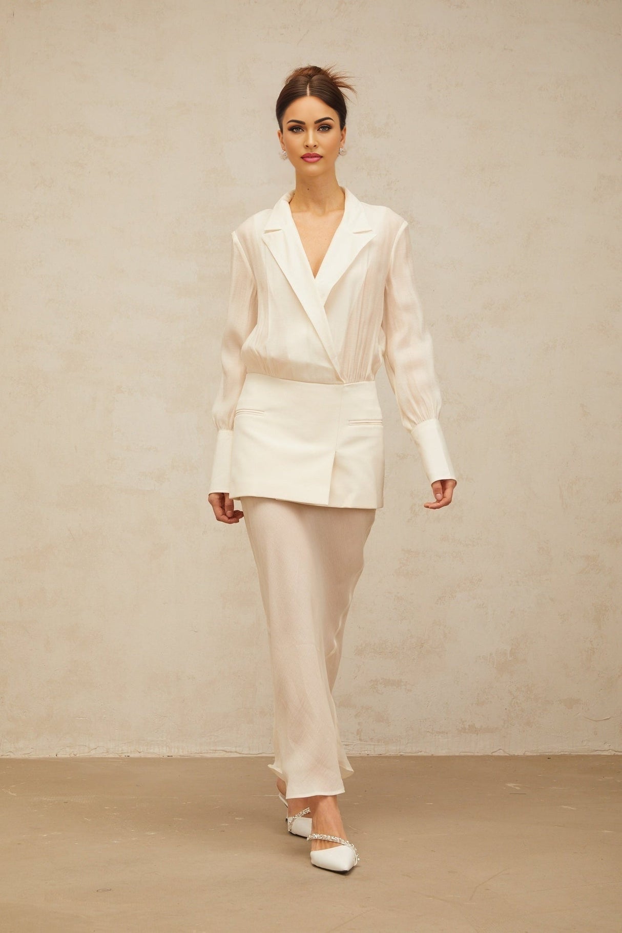 A woman wearing a long white maxi dress with sheer panels standing in a relaxed pose