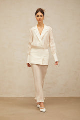A woman wearing a long white maxi dress with sheer panels standing in a relaxed pose