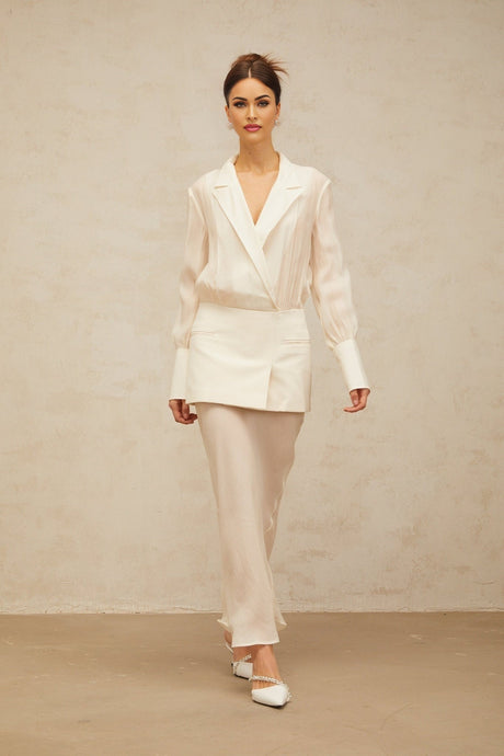 A woman wearing a long white maxi dress with sheer panels standing in a relaxed pose