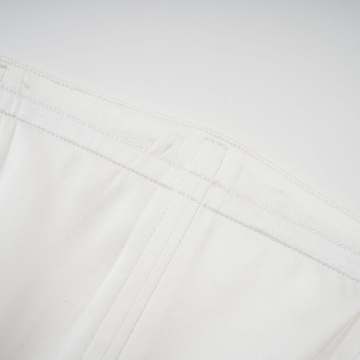 A woman wearing a long white pleated maxi dress with an offshoulder neckline