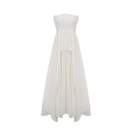 A woman wearing a long white pleated maxi dress with an offshoulder neckline