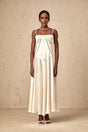 A woman wearing a long white satin dress with a flared skirt standing against a plain background