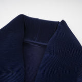 A woman wearing a matching blue patterned outfit consisting of a flowing cape and a skirt with creased texture