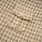 A woman wearing a matching gold tweed jacket and skirt set with sequin embellishments The jacket has long sleeves and the skirt is knee length Both pieces shimmer in the light