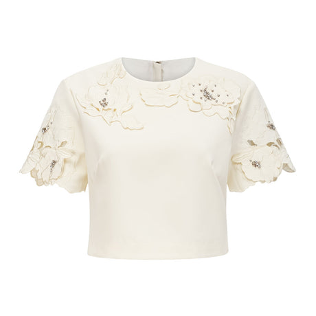 A woman wearing a matching neutralcolored top and skirt set with 3D floral petal details The top is sleeveless and the skirt is kneelength Both pieces feature delicate textured petals in a soft beige shade creating an elegant and feminine ensemble