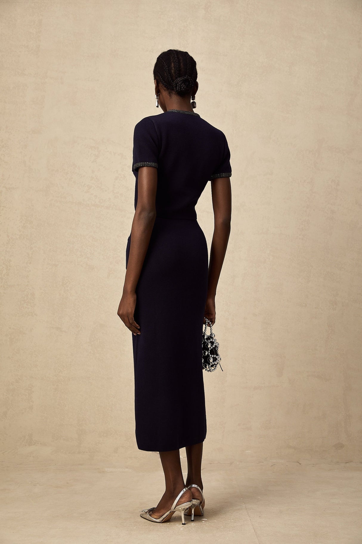 A woman wearing a matching ribbed knit top and skirt set in a light color The set features embellishments and a form fitting silhouette