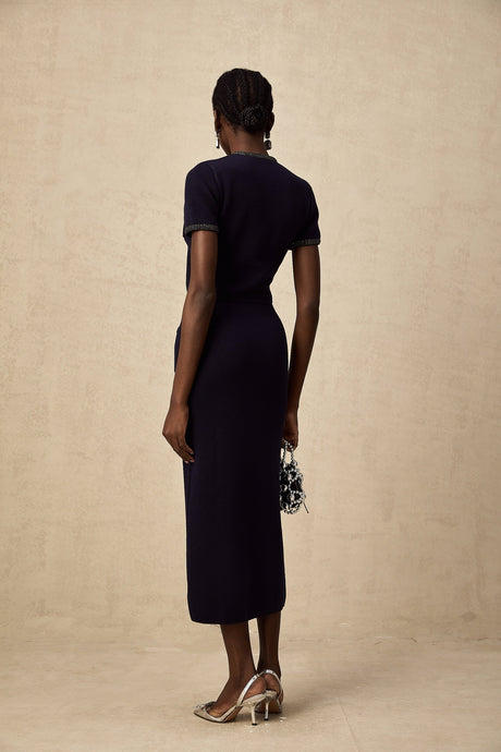A woman wearing a matching ribbed knit top and skirt set in a light color The set features embellishments and a form fitting silhouette