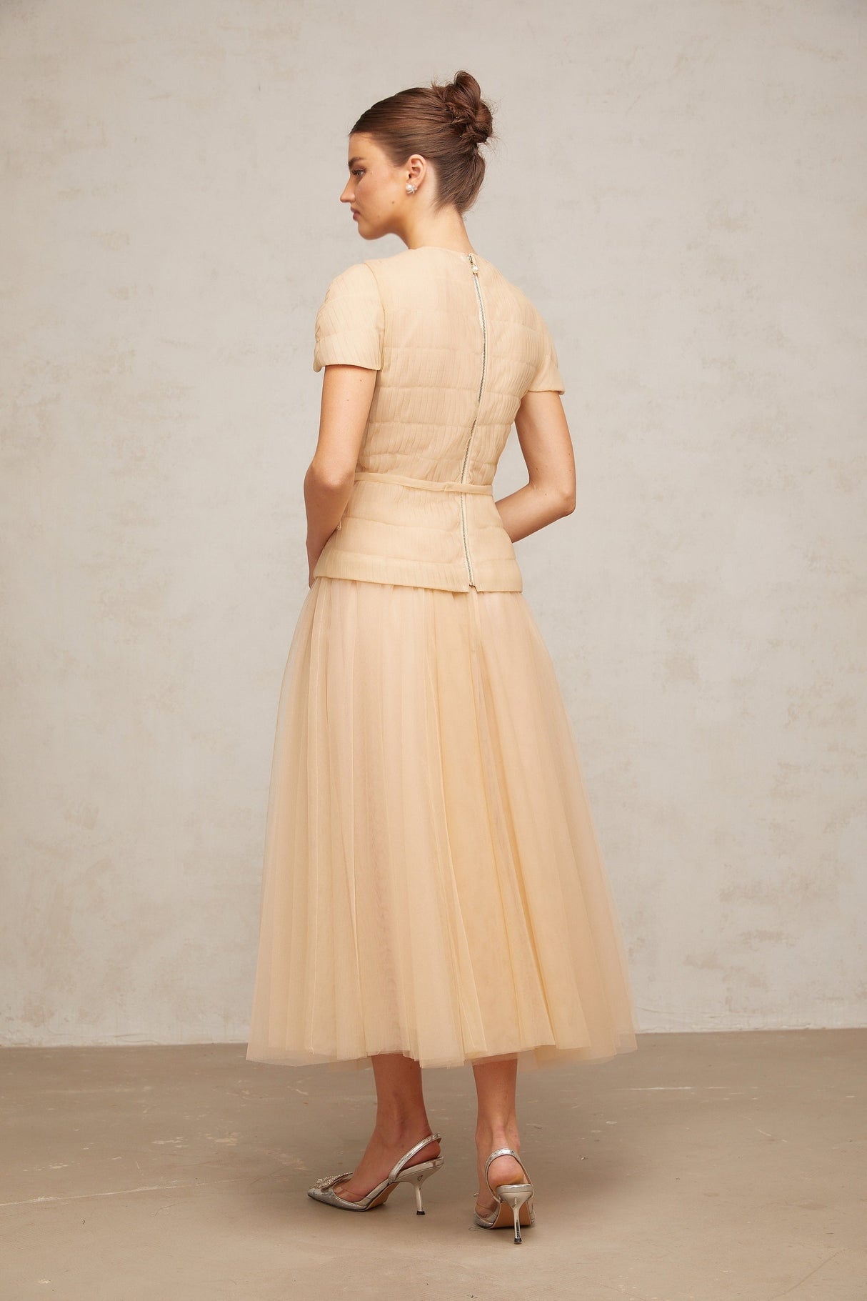 A woman wearing a matching set consisting of a sheer tulle top and skirt adorned with delicate floral appliques in a light color palette