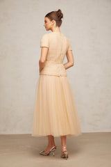 A woman wearing a matching set consisting of a sheer tulle top and skirt adorned with delicate floral appliques in a light color palette
