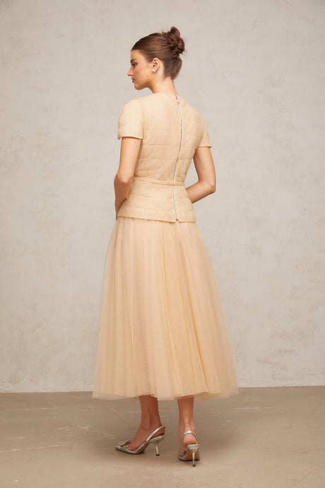 A woman wearing a matching set consisting of a sheer tulle top and skirt adorned with delicate floral appliques in a light color palette