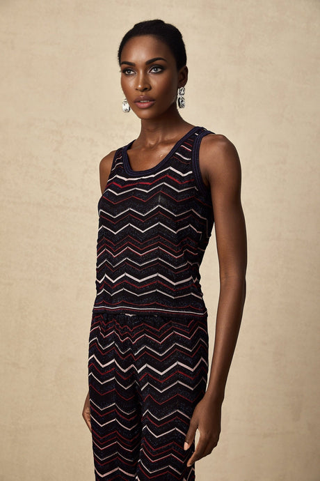 A woman wearing a matching set consisting of a zigzag patterned crochet knit top and trousers in the Emmanuelle style The outfit features an intricate woven design and a coordinated look
