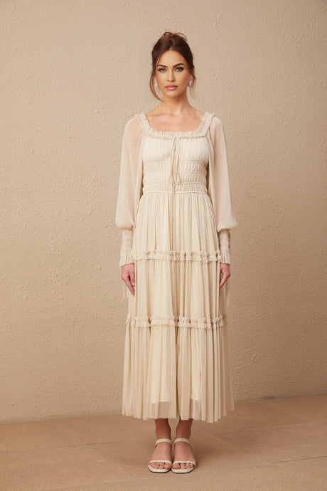 A woman wearing a metallic pleated midi dress with shirred detailing and a flowy silhouette named Camille